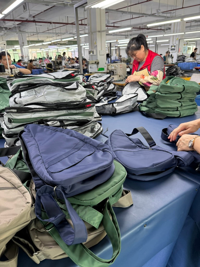 Factory setting with workers assembling bags on a table.